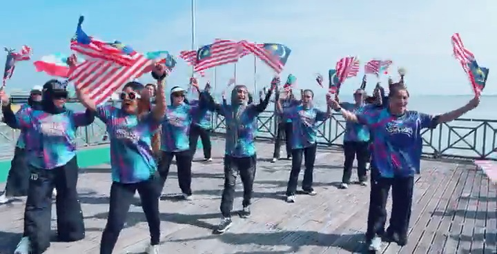 Participants holding Malaysian flags by the waterfront